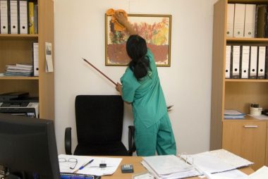 maid cleaning frame on wall